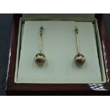 A pair of 9ct gold stud earrings having facetted diamond cut spheres on bar drops, approx 2.4g