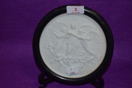 A Victorian parian ware roundel plaque depicting three angels surrounded by cherubs