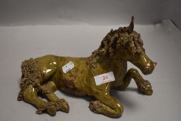 A studio pottery figure of a unicorn signed MH having naturalistic glaze