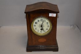 An Edwardian mahogany mantel clock having ornate enamel dial