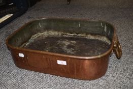 A large copper baking tray or cooking pan with twin handles