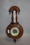 An Edwardian stipple carved barometer with enamelled dial and thermometer scale