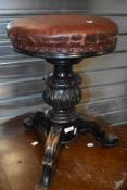 A 19th Century stained frame piano stool having leather seat, carved column and triple scroll legs
