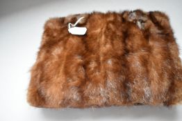 A mink fronted muff having heads attached with zip compartment to gathered reverse.