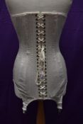 A vintage heavily boned long line under bust corset having satin finish and metal suspender clasps.