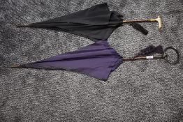 Two antique umbrellas, a purple fabric example having HM silver handle,the other with black with