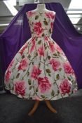 A stunning 1950s sun dress having vibrant rose pattern in cerise, pink and green boasting square