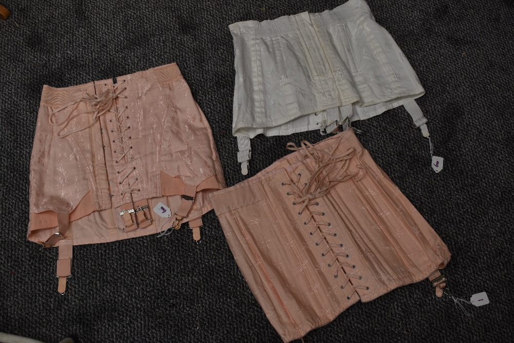 A trio of vintage boned girdles having metal suspender clasps, two pink and one white. - Image 2 of 2