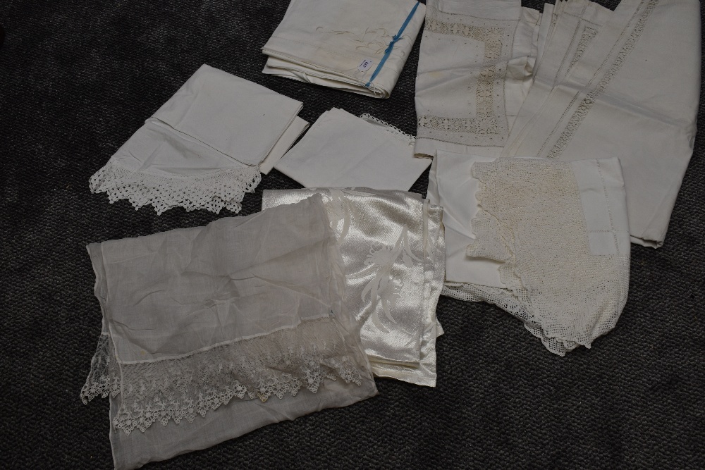 An assortment of antique linen, including damask table cloths and bed sheet, and deep crotchet edged