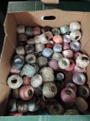 A box full of vintage and antique reels of thread, many colours and some lovely advertising labels.