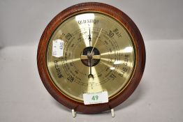 A circular weathermaster wall barometer having brass dial with glass face on wooden mount.