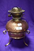 An interesting Arts and Crafts oil burner, hammered effect body with scrolled brass legs, devoid