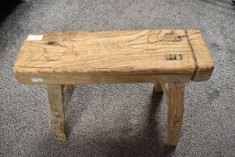 An antique rustic elm stool having four legs with stretchers between.