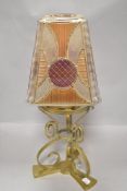 A Victorian Arts and Crafts oil lamp stand in brass with pressed glass shade in orange and purple