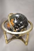 A traditional styled multi directional semi precious stone globe sat on silver tone legs.