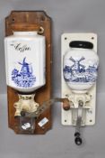 Two vintage wall mounted coffee grinders having blue and white scenes to ceramic containers and