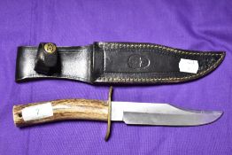 A stainless blade knife with rounded antler handle and brass guard, lanyard hole and embossed