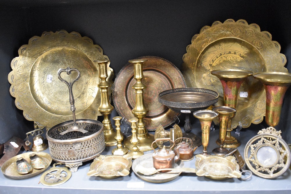 A mixed lot of metal ware to include brass candlesticks, photo frame, chargers and more.