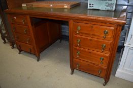 An early 20th century office desk having two sets of four drawers with green leather top