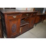 A Victorian side board or dresser base in mahogany with carved doors, triple drawers and cupboards