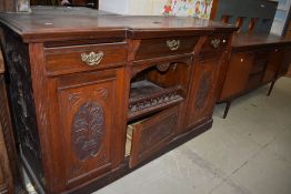 A Victorian side board or dresser base in mahogany with carved doors, triple drawers and cupboards