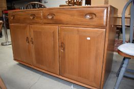 A mid century Ercol sideboard having double drawer and under cupboard space in mid stain