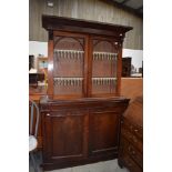 A Victorian side board base unit in mahogany with similar book case top having rolled glass doors