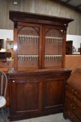 A Victorian side board base unit in mahogany with similar book case top having rolled glass doors