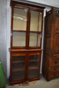A late 19th/early 20th century mahogany library book case having rolled glass doors