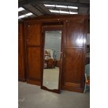 An Edwardian mahogany and inlaid triple wardrove having mirror door