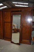 An Edwardian mahogany and inlaid triple wardrove having mirror door
