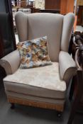 A traditional wing backed arm chair having cream upholstery.