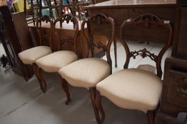 A set of four Victorian balloon back dining chairs having carved fruit and leaf backs on cabriole