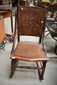 An antique rocking chair having wood back with cut out detailing to form a pattern.