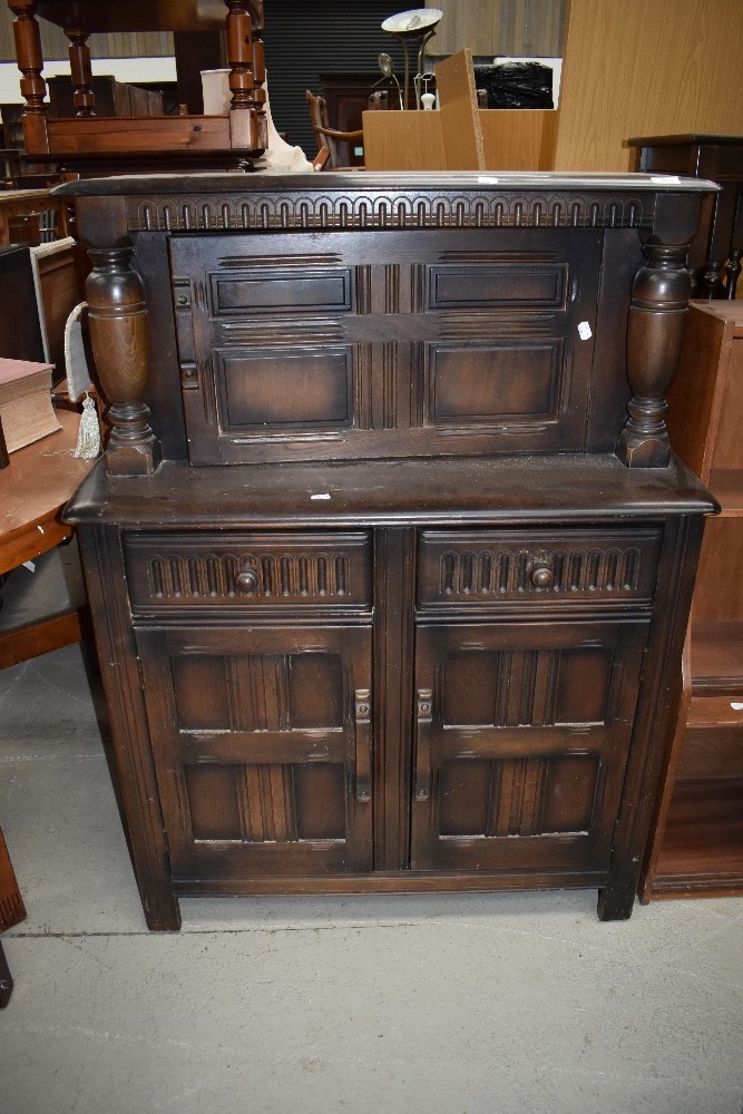 A 20th century dark oak sideboard having under and over cupboard with two...