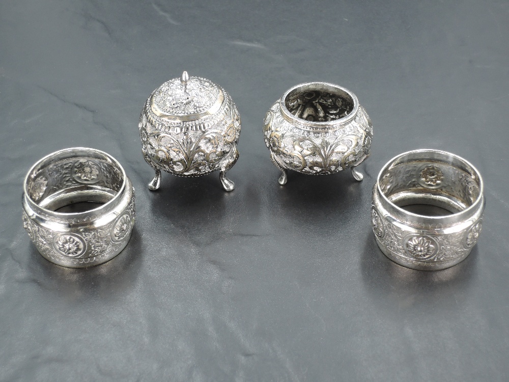 A pair of Eastern white metal condiments, with moulded foliate scroll...