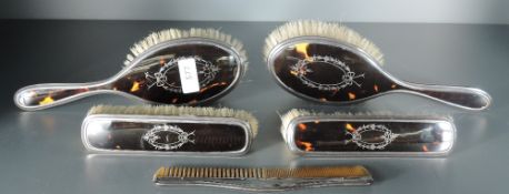 A George V silver six-piece silver and tortoiseshell dressing table set, comprising a hand mirror,