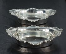 A pair of Edwardian silver dishes, of oval form with broad C-scroll moulded rim, Marks for