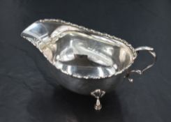 A George V silver sauce boat, of traditional form with scroll-moulded rim and generous spout,