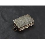 A Victorian silver vinaigrette, of shaped and hinged rectangular form with engraved detail, the