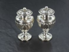 A pair of 19th century silver pepperettes, of urn-form with pierced finial topped pull-off covers