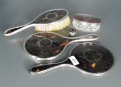 A George V silver and tortoiseshell six-piece dressing table set, comprising two hair brushes,