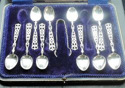 An incomplete cased set of ten silver teaspoons and sugar tongs with pierced Welsh love spoon type