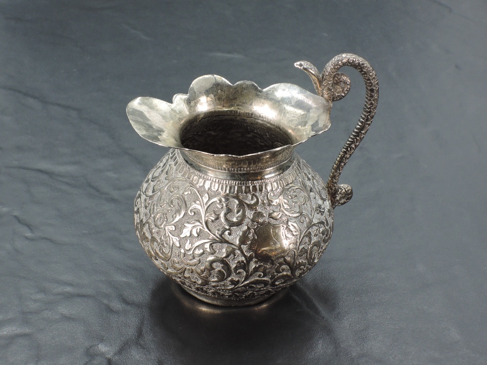 An eastern white metal cream jug, of baluster form with flared rim and...