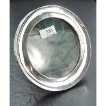 An Edwardian silver photograph frame of circular form having green leather covered easel back,