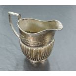 An Edwardian silver milk jug, of oval form with generous spout and angular handle, over the half