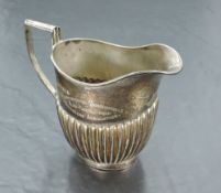 An Edwardian silver milk jug, of oval form with generous spout and angular handle, over the half