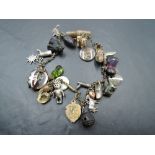 A gilt metal charm bracelet/necklace, suspended with a variety of charms, to include a bog oak