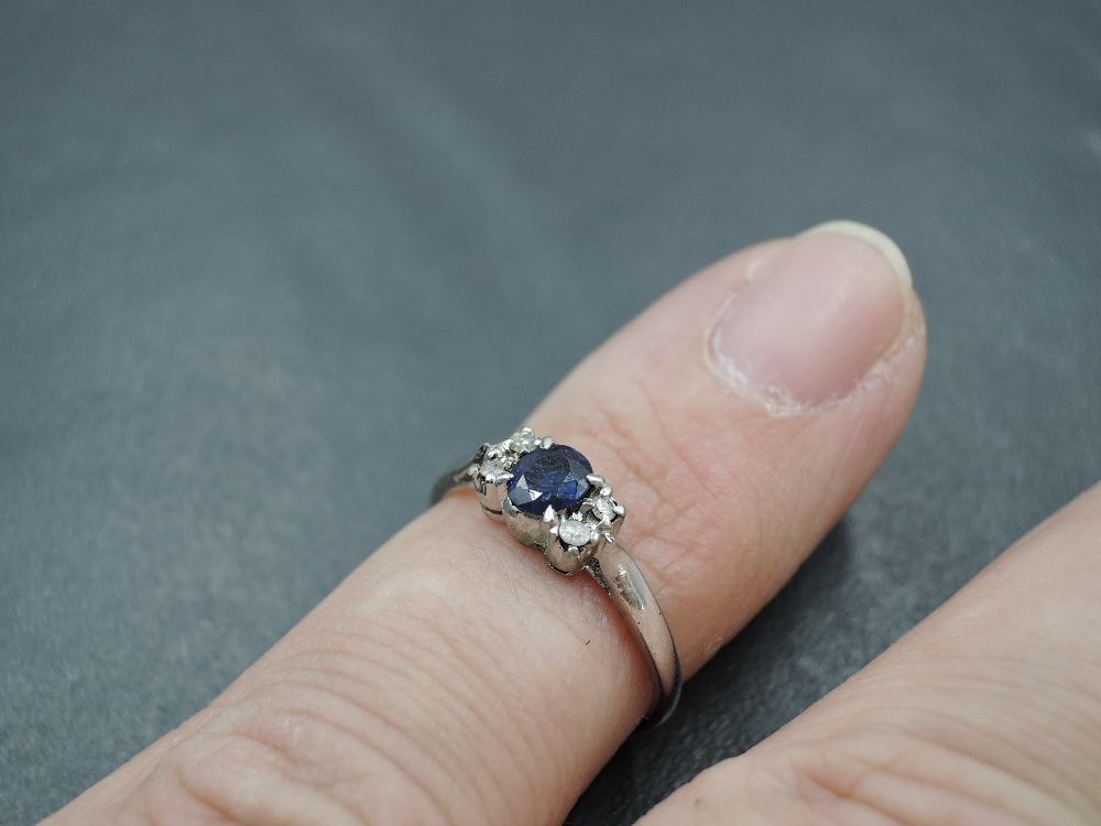 A sapphire dress ring flanked by diamond chips with knife blade shoulders on a white metal loop, - Image 4 of 4