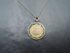 A 9ct gold medalion with engraved decoration and monogram on a yellow metal chain, approx 5.4g